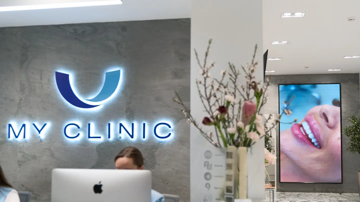Стойка ресепшена My Clinic с подсвеченным логотипом и цветами